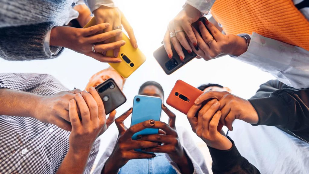 Multiple colorful smartphones held by people, representing the diverse use of mobile devices in modern society